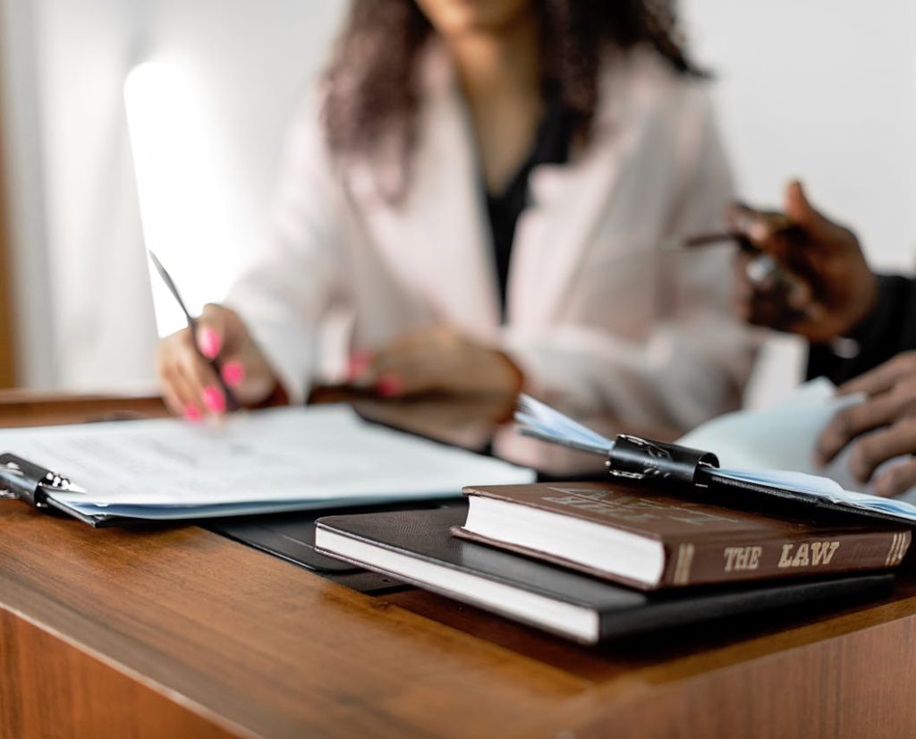 Two lawyers reviewing documents with law books on a desk. Professional legal environment.