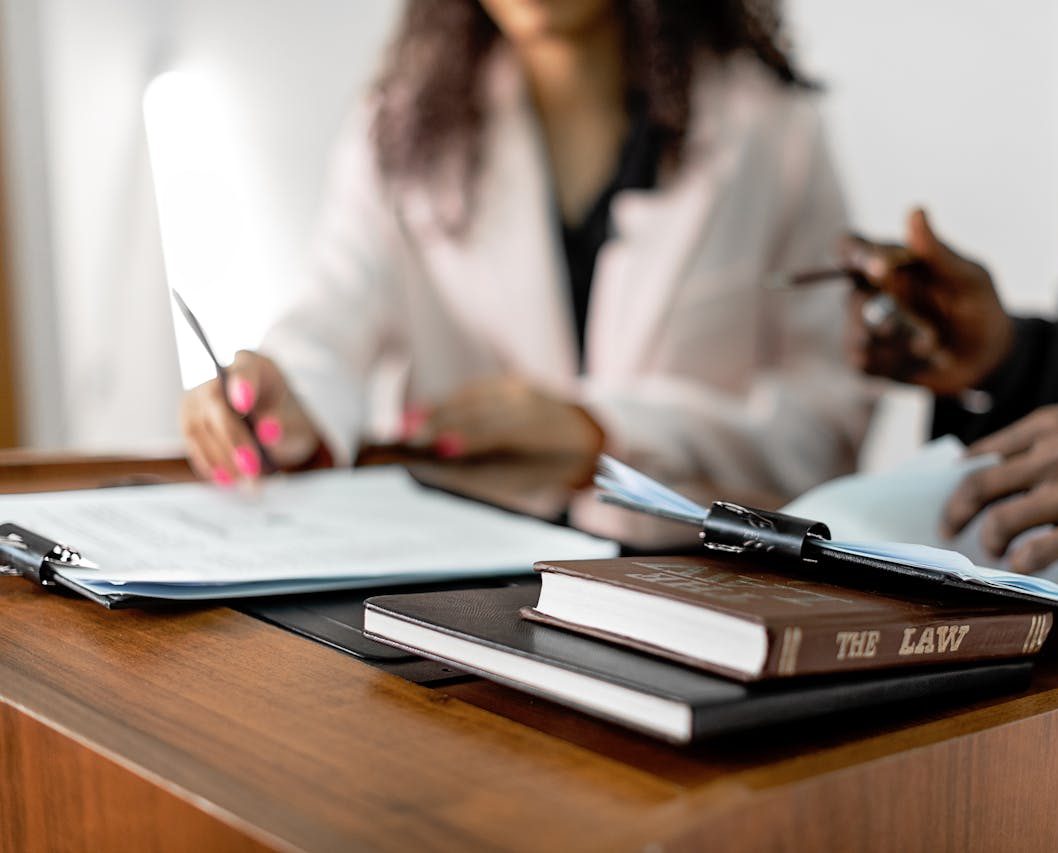 Two lawyers reviewing documents with law books on a desk. Professional legal environment.